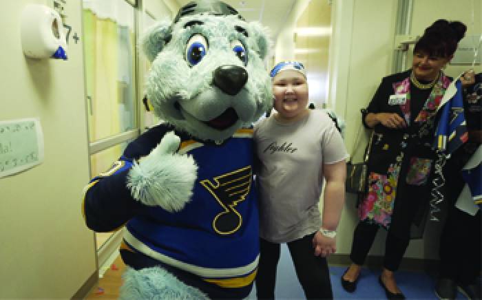 A young girl with the Blues' Hockey Mascot: A polar bear with a blue jersey on.