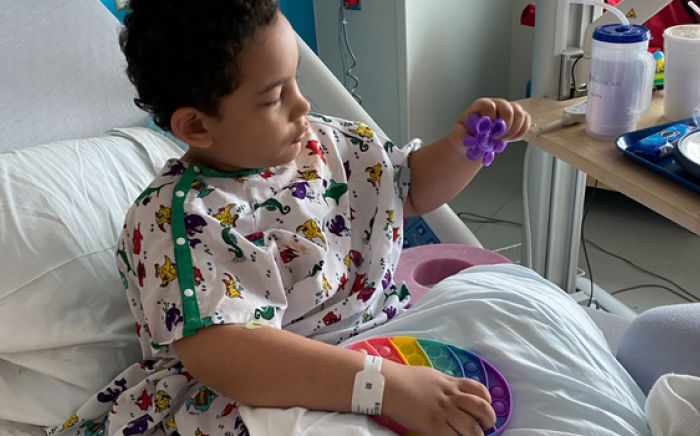 A boy in a hospital bed plays with toys.
