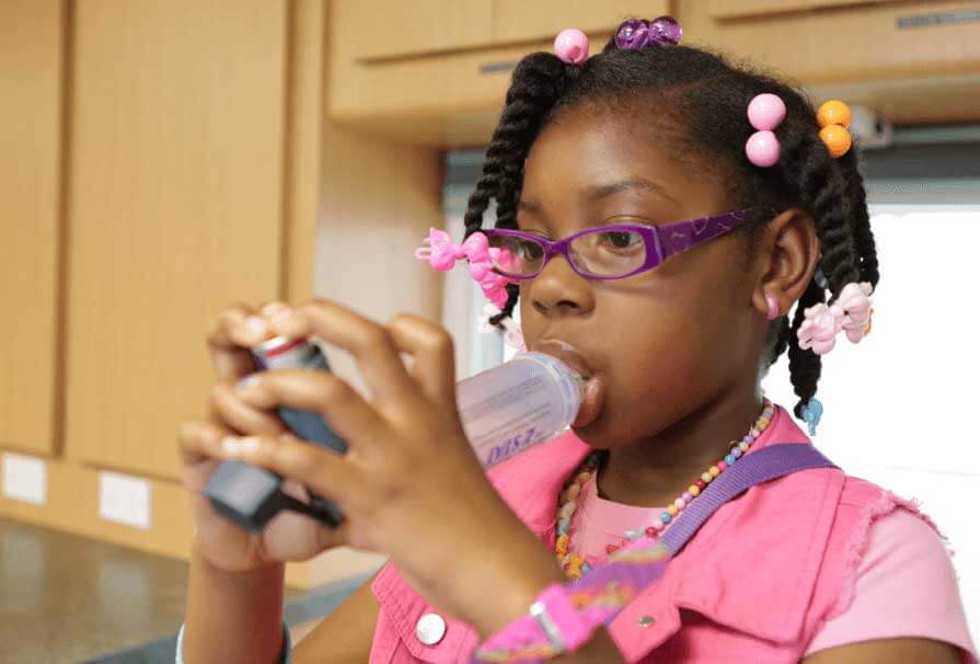 Kid using an asthma inhaler inside Healthy Kids Express mobile unit