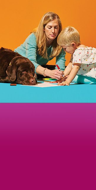 Child drawing with service dog and helper