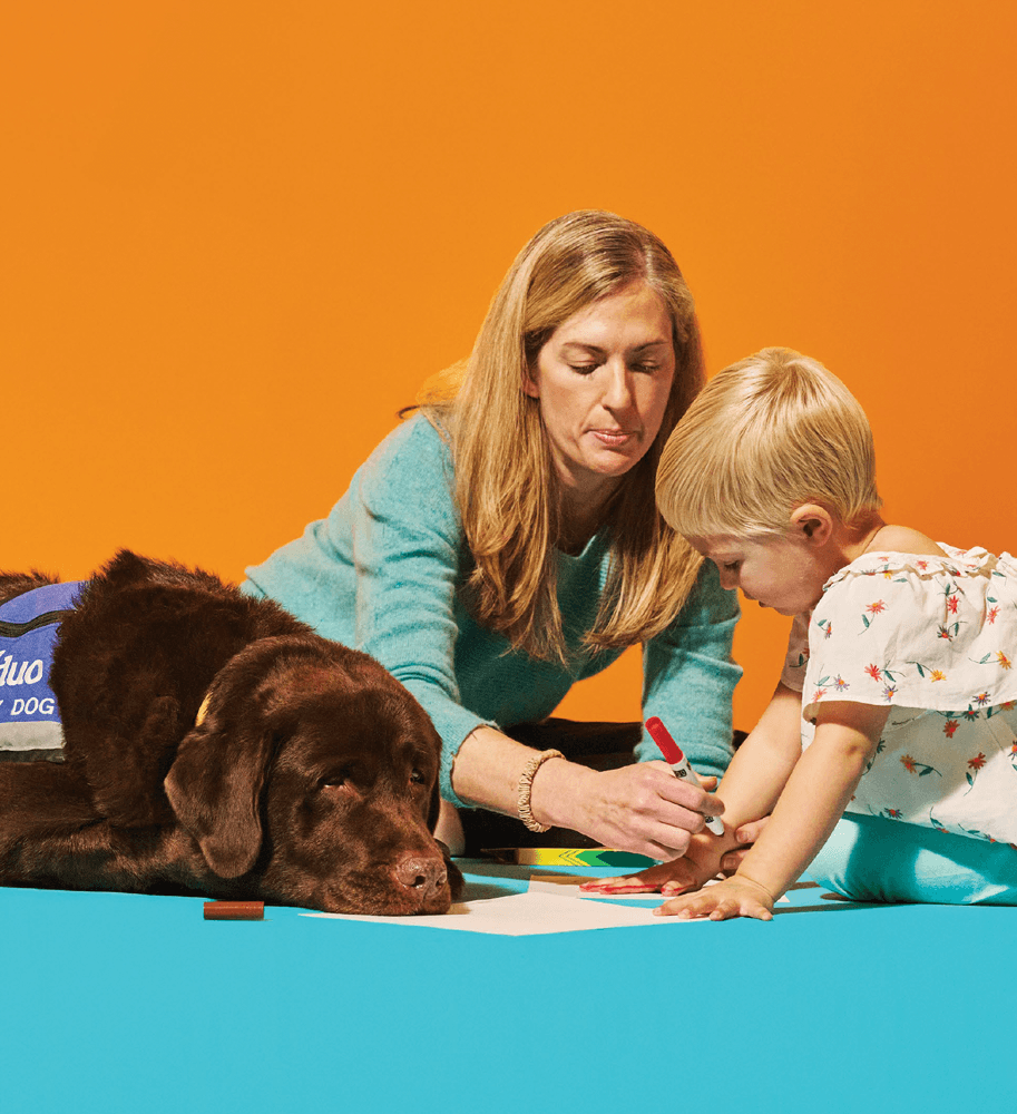Child drawing with helper and service dog