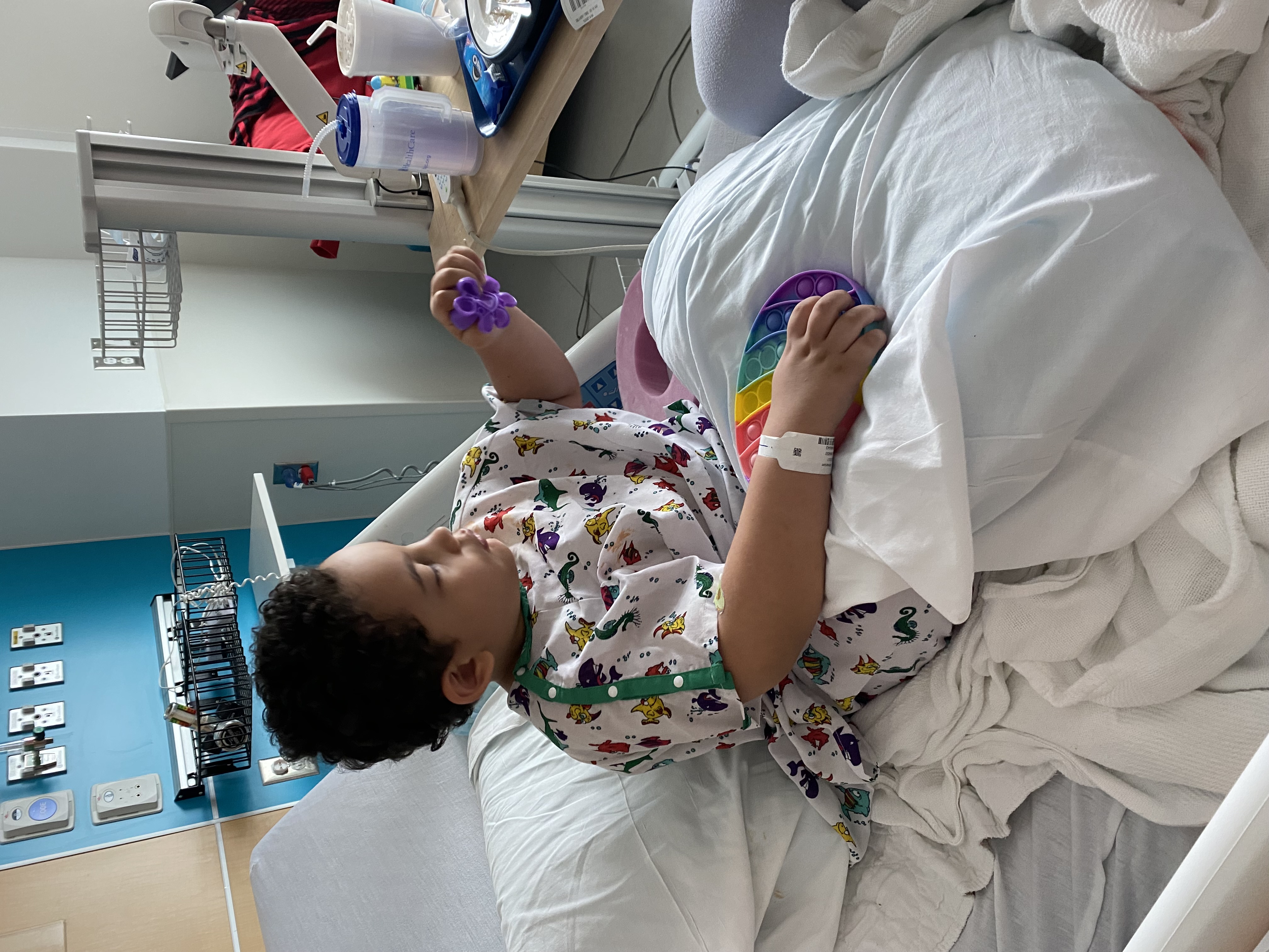 Boy in hospital bed playing with toys.
