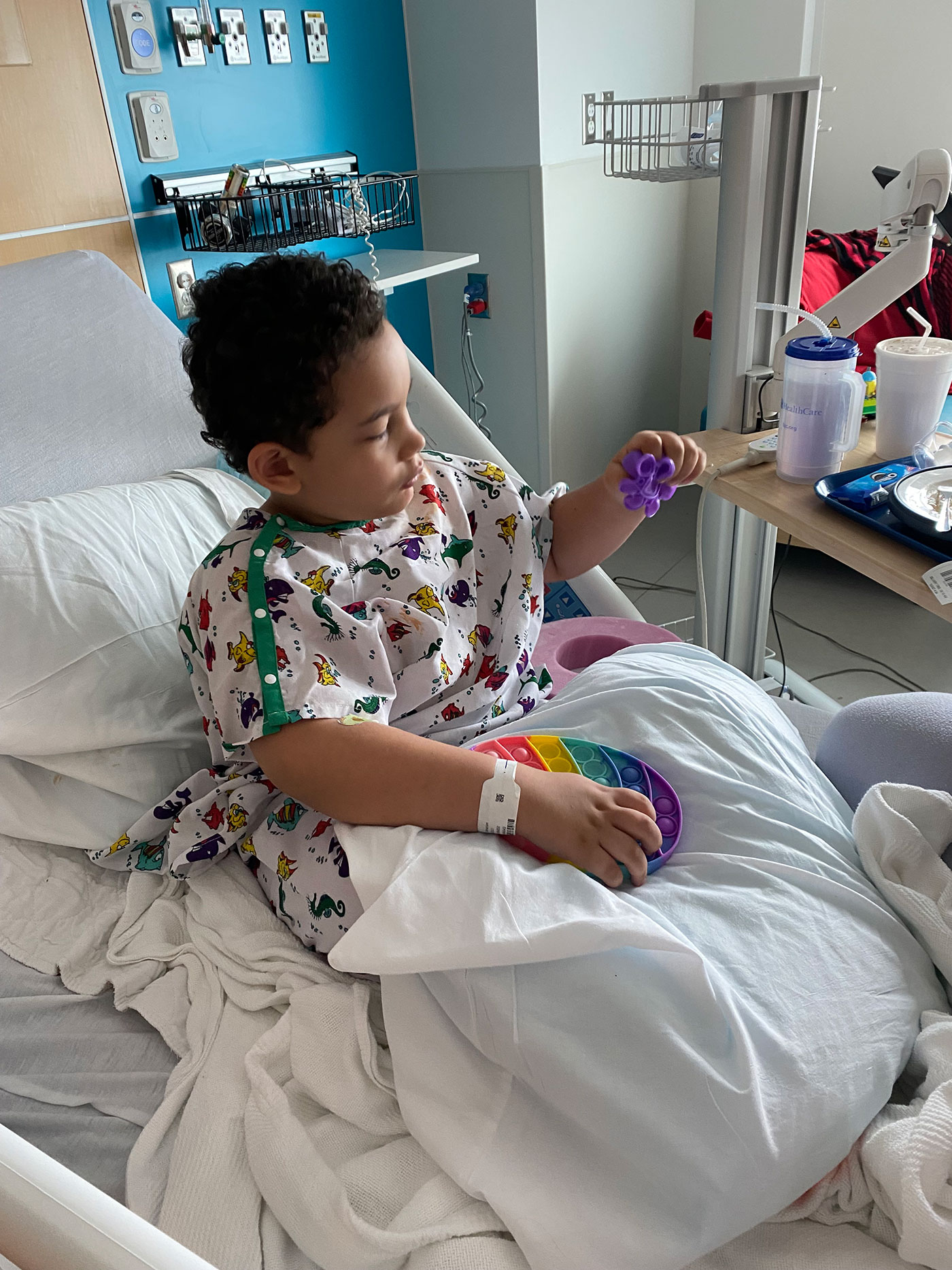 Boy in hospital bed playing with toys.