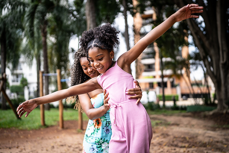 Two young girl helping each other learn how to balance on their legs