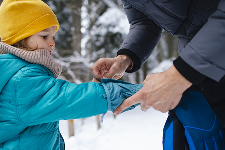 Parent helping fit/adjust the jacket sleeve of a child