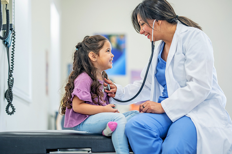 Doctor examining a young girl using a stethoscope at the doctor's office
