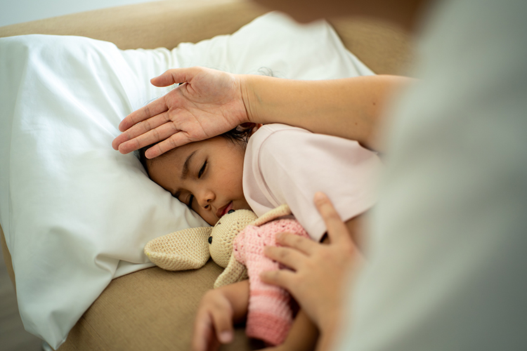 Mom checking the temperature of a daughter's forehead using her hand