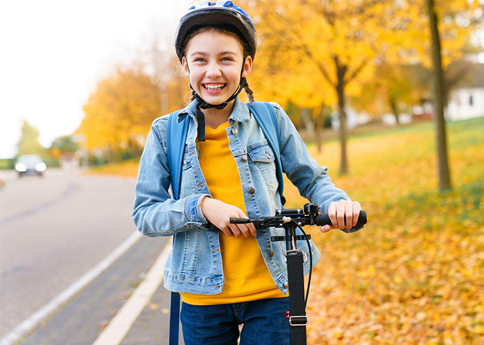Young girl riding a scooter with a helmet on