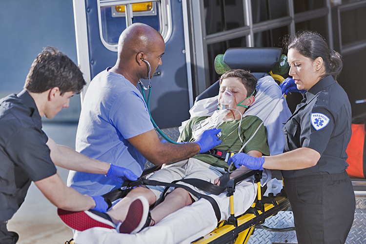 Paramedic team and doctor examining a young boy on an ambulance stretcher