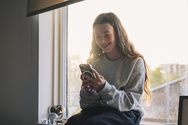 Young girl smiling while using her phone