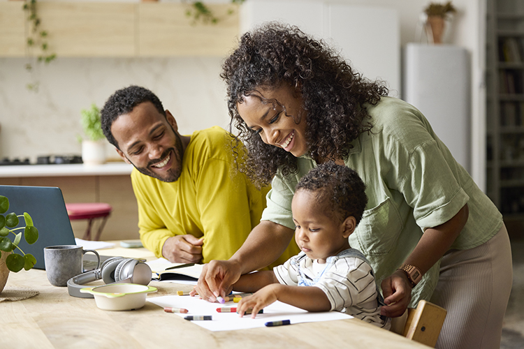 Mom and dad teaching their young child how to draw with crayons