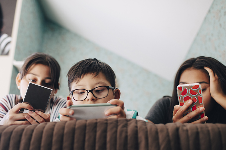 Three young kids looking at their phones