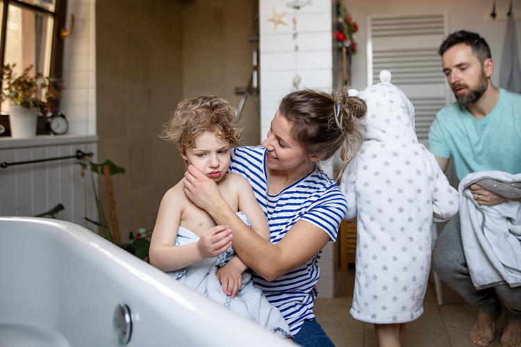 Mom holding child who is refusing a shower