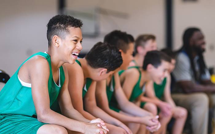Athlete kids sitting on a bench and laughing