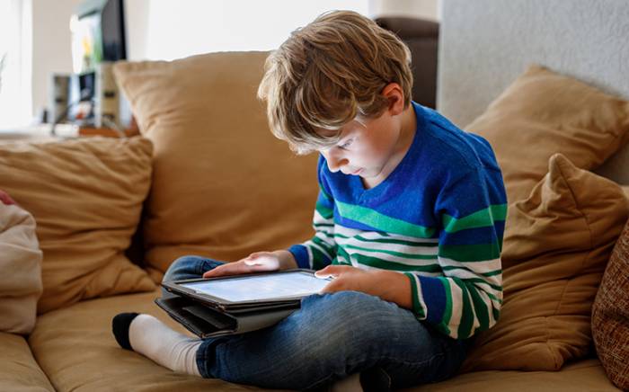 Young boy looking at a tablet while sitting on a couch