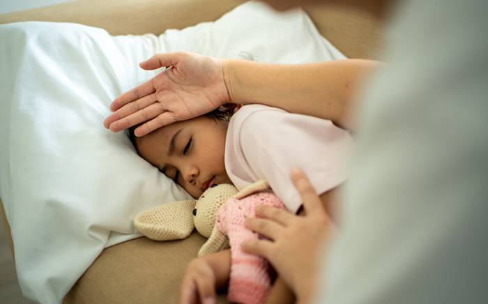 Mom checking the temperature of a daughter's forehead using her hand