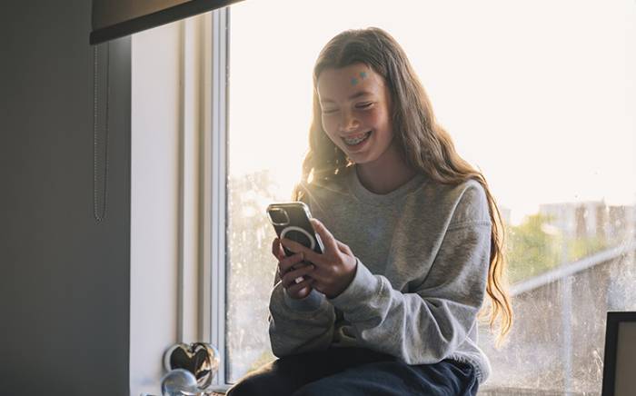Young girl smiling while using her phone