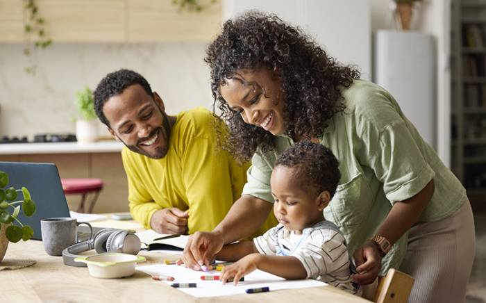 Mom and dad teaching their young child how to draw with crayons