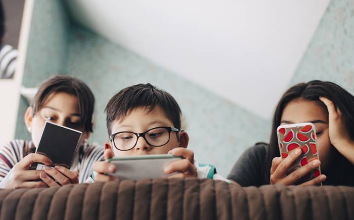 Three young kids looking at their phones