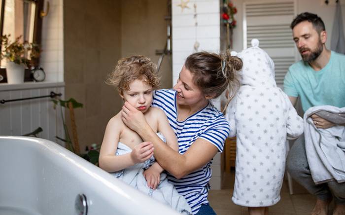 Mom holding child who is refusing a shower